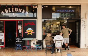 Customers sitting at an outdoor table outside Phoencian Falafel.