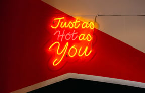 A fluorescent sign that says 'just as hot as you'.
