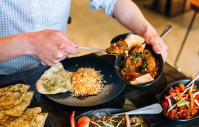 Indian food being scooped onto a plate.