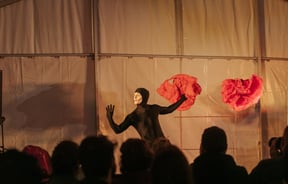 A man dressed in a black holding a red piece of fabric.