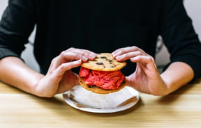 Two hands holding an ice cream cookie sandwich.
