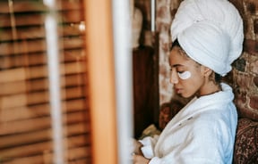 Women in spa with under-eye skincare patches wearing a dressing gown and towel wrapped around head