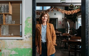A woman in her cafe posing for the camera.