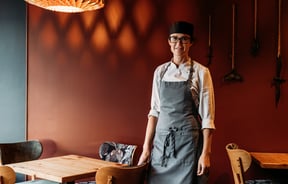 A female chef in a restaurant smiling to camera.