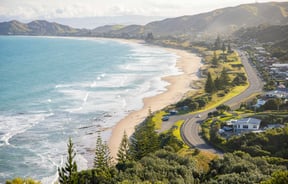 Road runs alongside the coastline, the waves on the beach meet the sand.