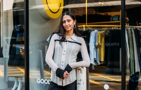A woman wearing black and white standing in front of a clothing store.