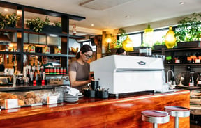 A woman making coffee at a coffee machine.