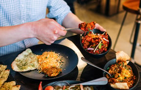 A man's hand serving himself at an Indian restaurant.