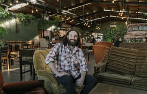 Chef Pedro Johnston sitting on couch smiling at Scoundrel in Christchurch