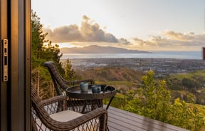 Table and chairs on a balcony overlooking the coastline.