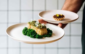 Waiter holding two vegan dishes at Hillside Kitchen in Wellington.