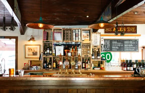 A wooden bar with green downlights where there are 4 beers on tap.