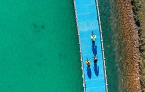 Three people biking on a bike trail over water.