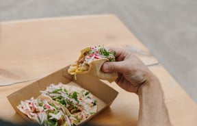 A hand holding a taco.
