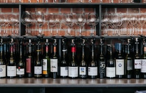 Bottles of red wine lined up in a row on a table.