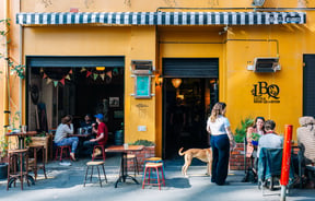 People dining outside a bar that has a yellow painted exterior.