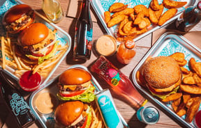 Birds eye view of silver trays filled with burgers and fries.