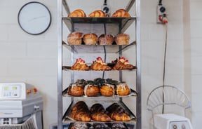 Silver trays of croissants and pastries stacked on top of each other in bakery kitchen