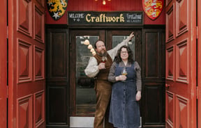 Owners of Craftwork standing outside the building with a pint in hand.