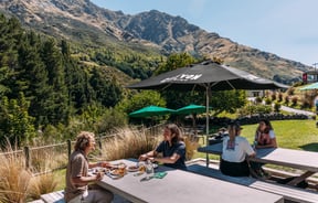 Four customers sitting at an outdoor table with nature scenery behind them.