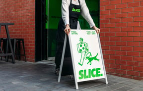 Someone putting Slice sandwich board sign outside shop