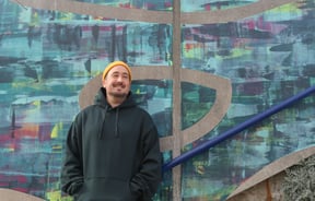 Image of male in yellow beanie infant of a painted wall.