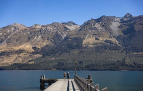 People standing on a wharf at a lake on a sunny day.