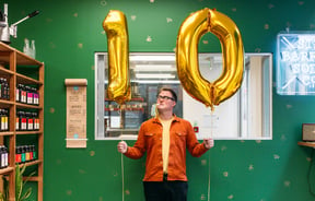 Joe Slatter holding two gold ballons with the numbers 1-0.