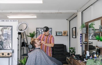 Man in the barbers seat getting a beard trim.