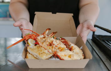 Takeaway box with cooked crayfish dish inside.