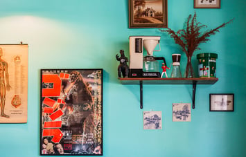 Wall art and curiosities on the shelf on the bright blue wall at Space Cadet, Hamilton.