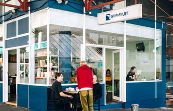 Exterior blue cafe with patrons eating outside.