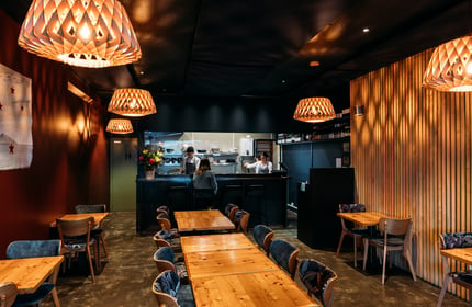 A woman sitting at the counter inside a dimly lit restaurant.
