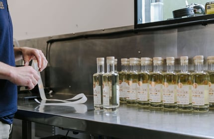 Bottles of gin lined up in a row waiting for stickers to be placed on them at Humdinger Gin Distillery in Geraldine.