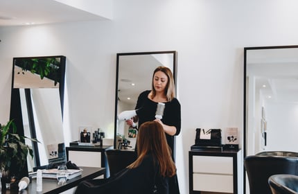 A woman blow drying hair inside Mod's Merivale hairdresser in Christchurch.