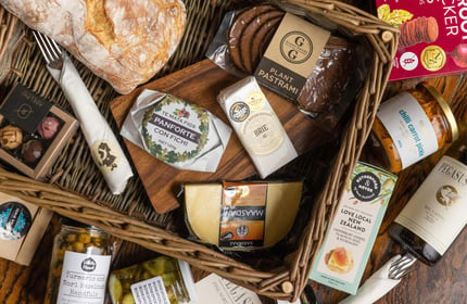 A flatlay of cheese and spreads in a basket.