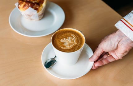 Waiter putting coffee and muffin down on cafe table