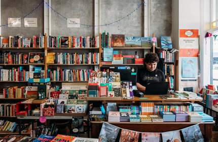 Male worker behind the counter of an independent bookstore in Petone Lower Hutt