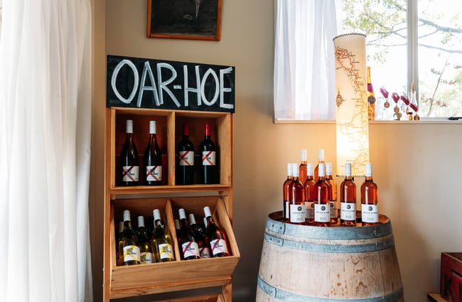 Wine bottles displayed on shelves and a barrel at Ōhau Wines.