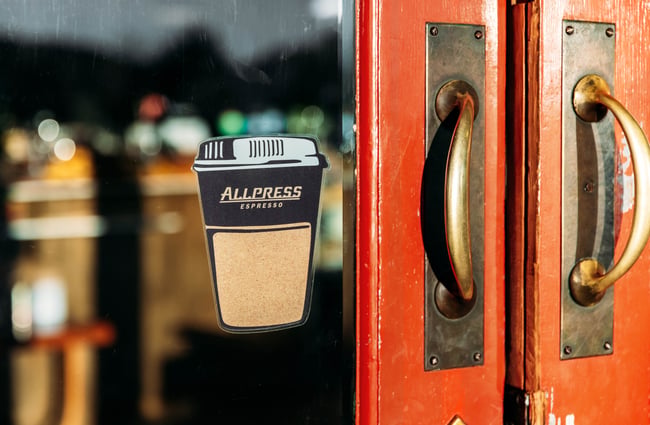 An Allpress sticker on a glass door.