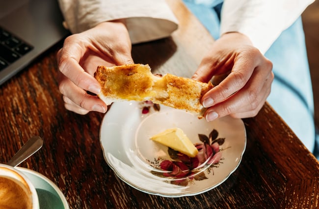 A close up of two hands pulling apart of a cheese roll.