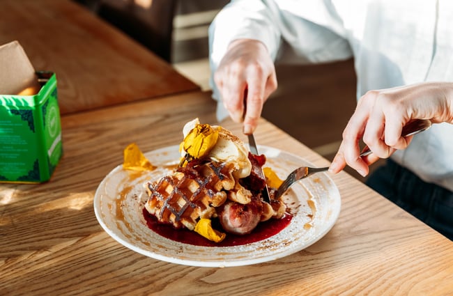 A person tucking into a plate of waffles.