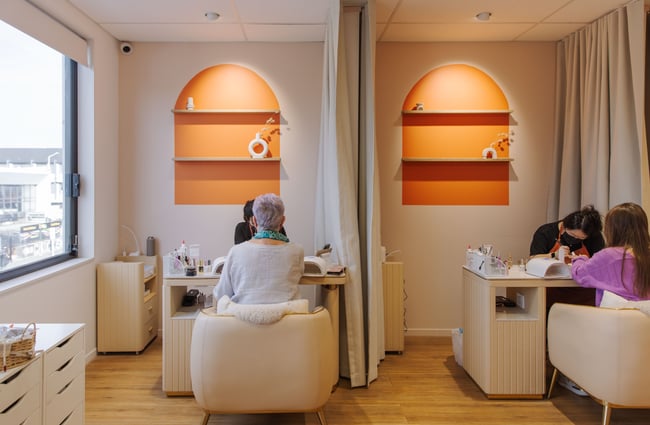 Customers sitting in chairs while getting their nails done.
