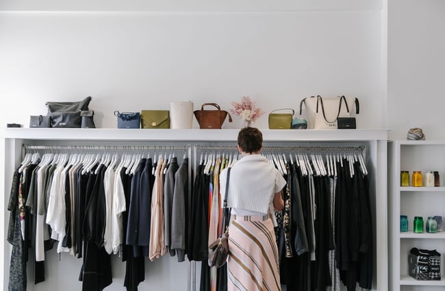 A customer browsing a rack of clothing inside 47 Frocks Wānaka.