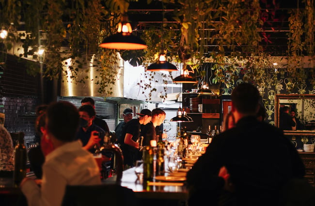 People sitting at the bar, looking at the chefs working in the open kitchen, at 5th Street, Christchurch.