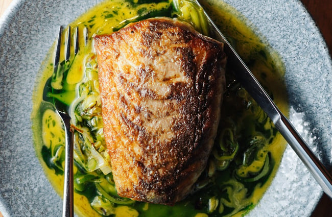 Close up of a seared fillet of fish in a shallow bowl of sauce at 5th Street restaurant Christchurch.