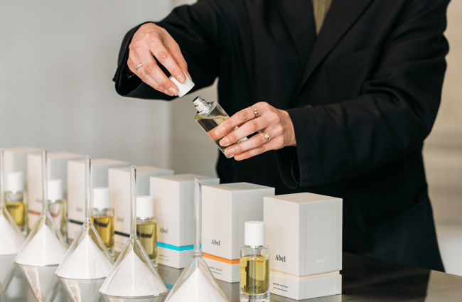 A lady in a black shirt opening a bottle of perfume.