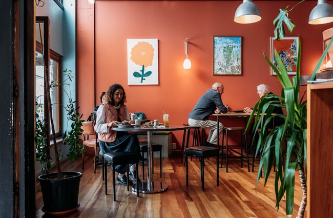 Customers sitting at low and high tables inside the cafe.