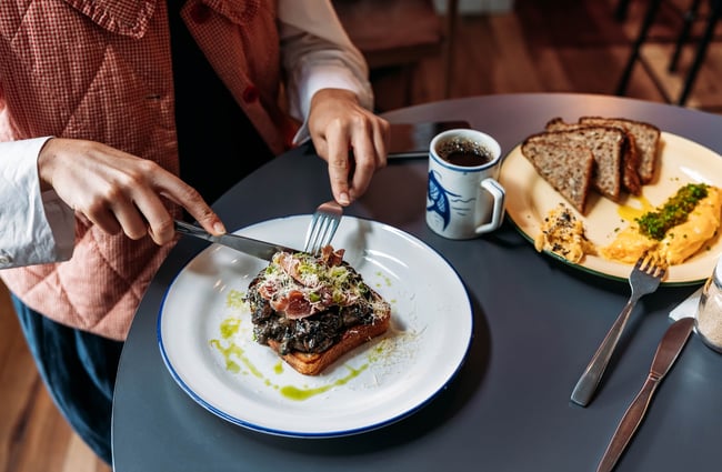 Close up of someone cutting into a mushrooms on toast dish.