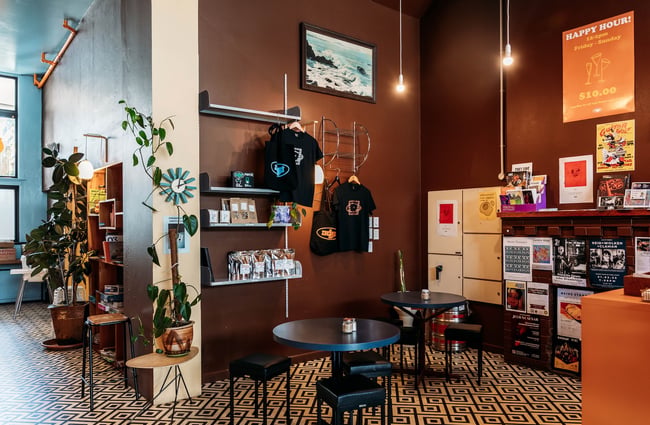 T-shirts and pantry goods for sale on wall-mounted shelves in a corner of the cafe.